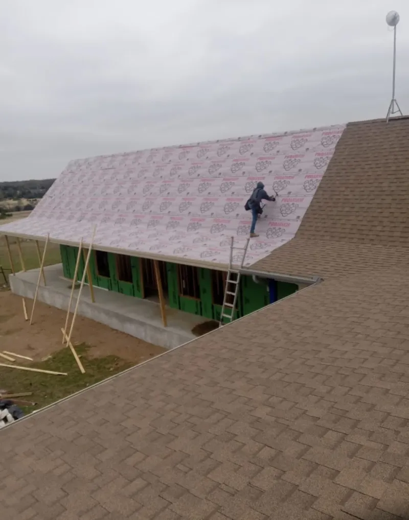 Worker preparing underlayment for a metal roof installation in Litchfield